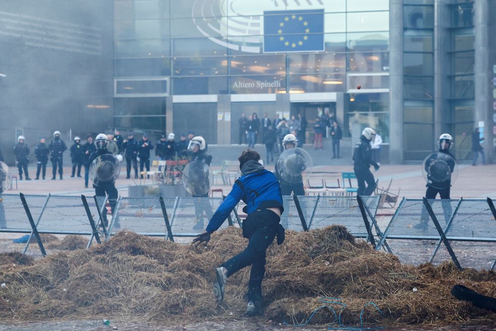 People protest outside the European Union headquarters as Belgian farmers use their tractors to block the headquarters
