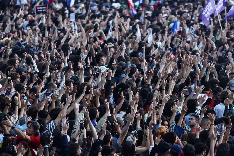 People raise their arms and hands as they gather at the Place de la Republique