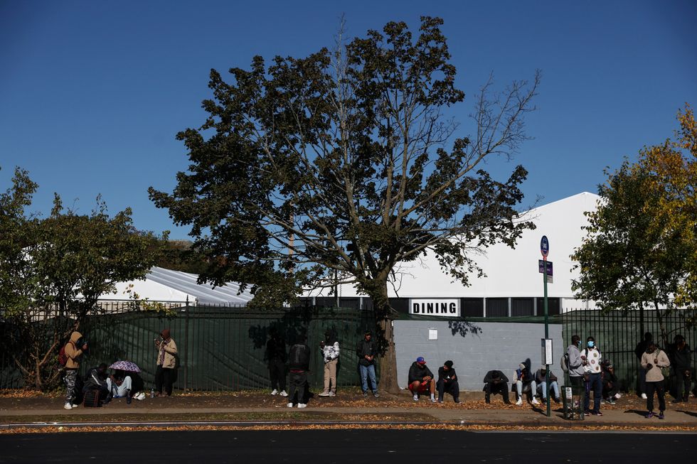 People seeking asylum sit outside a shelter built to house newly arrived migrants on the campus of the Creedmoor Psychiatric Facility in Queens
