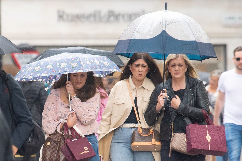 People shelter under umbrellas during a downpour of rain in Covent Garden, London, as parts of the UK are hit by heavy rain and thunderstorms. Picture date: Sunday July 4, 2021.