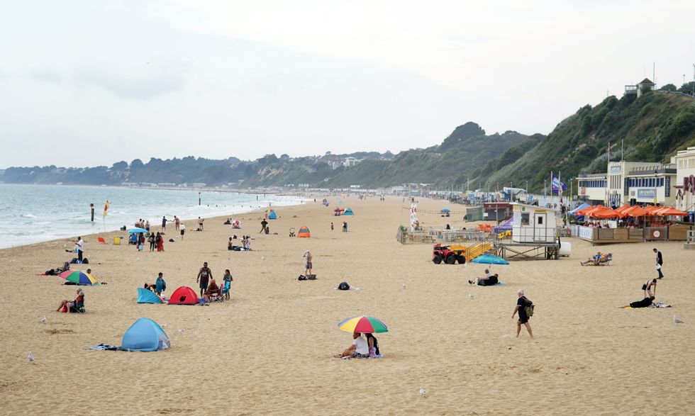 People sit under a cloudy sky on Bournemouth Beach in Dorset.