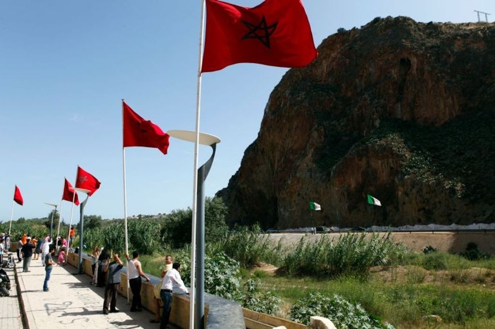 People stand near a border post on the Algerian side of the Morocco-Algeria border
