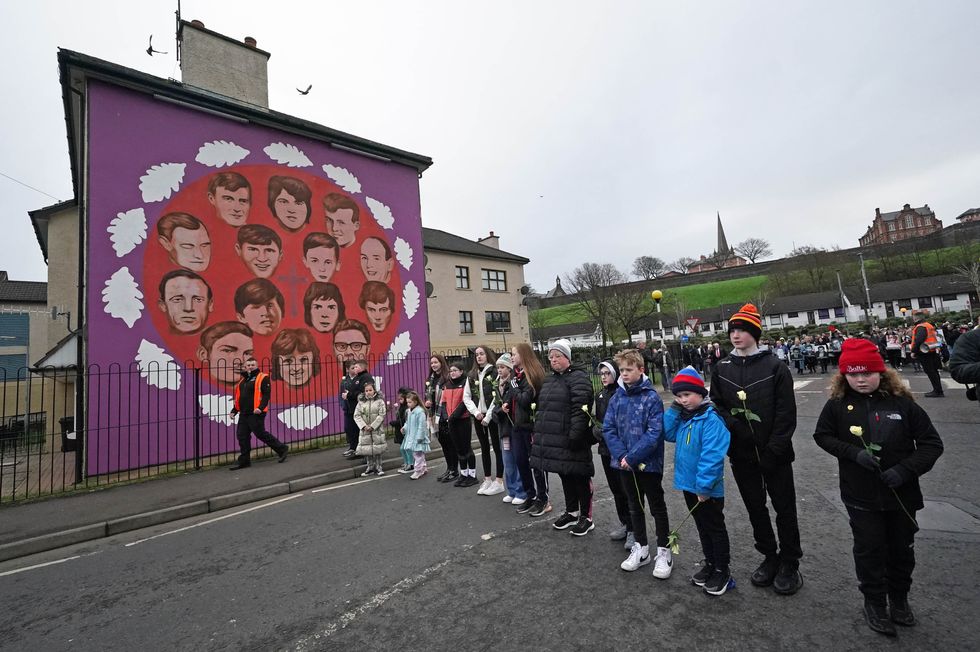People stop at a mural showing the 14 Bloody Sunday victims during a remembrance walk in Derry to mark the 50th anniversary of Bloody Sunday. Picture date: Sunday January 30, 2022.