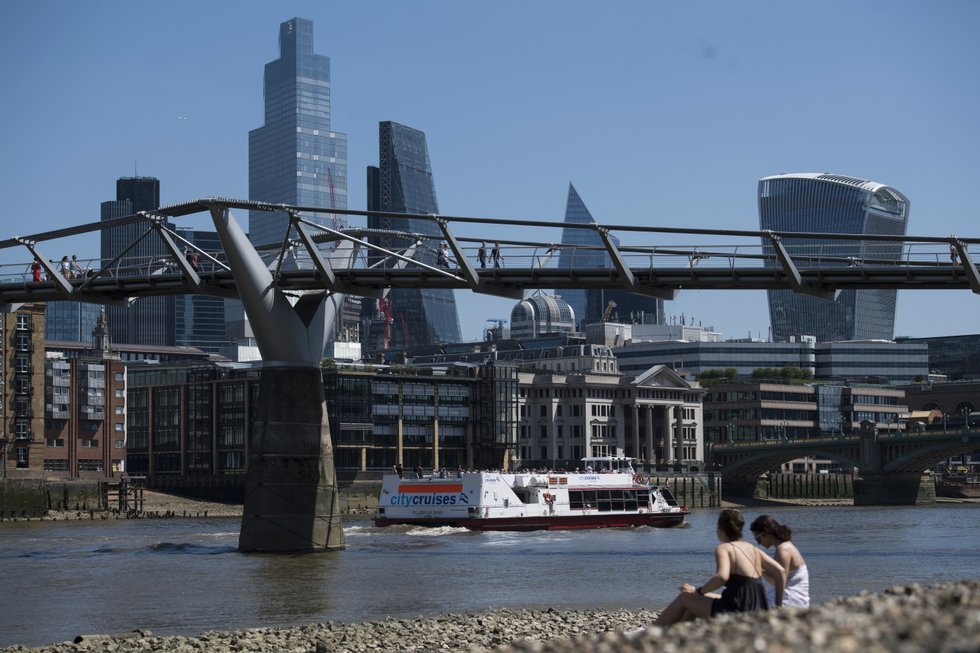 People sunbathe on the river bank near Millennium Bridge, in London. Southern England could see the hottest day of the year on Monday.