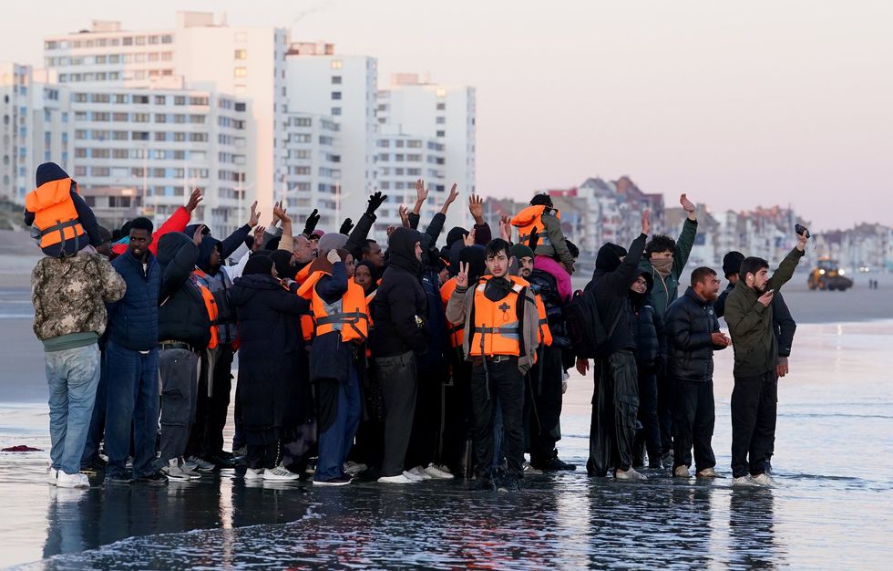 People thought to be migrants attract a boat on the beach off the coast of Dunkirk, France