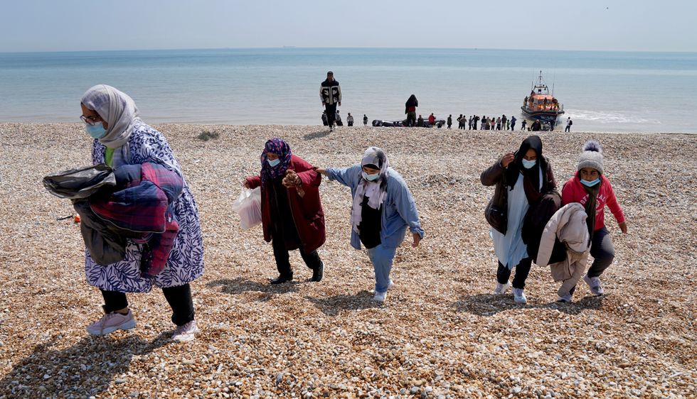 People thought to be migrants making their way up the beach after arriving on a small boat at Dungeness in Kent.