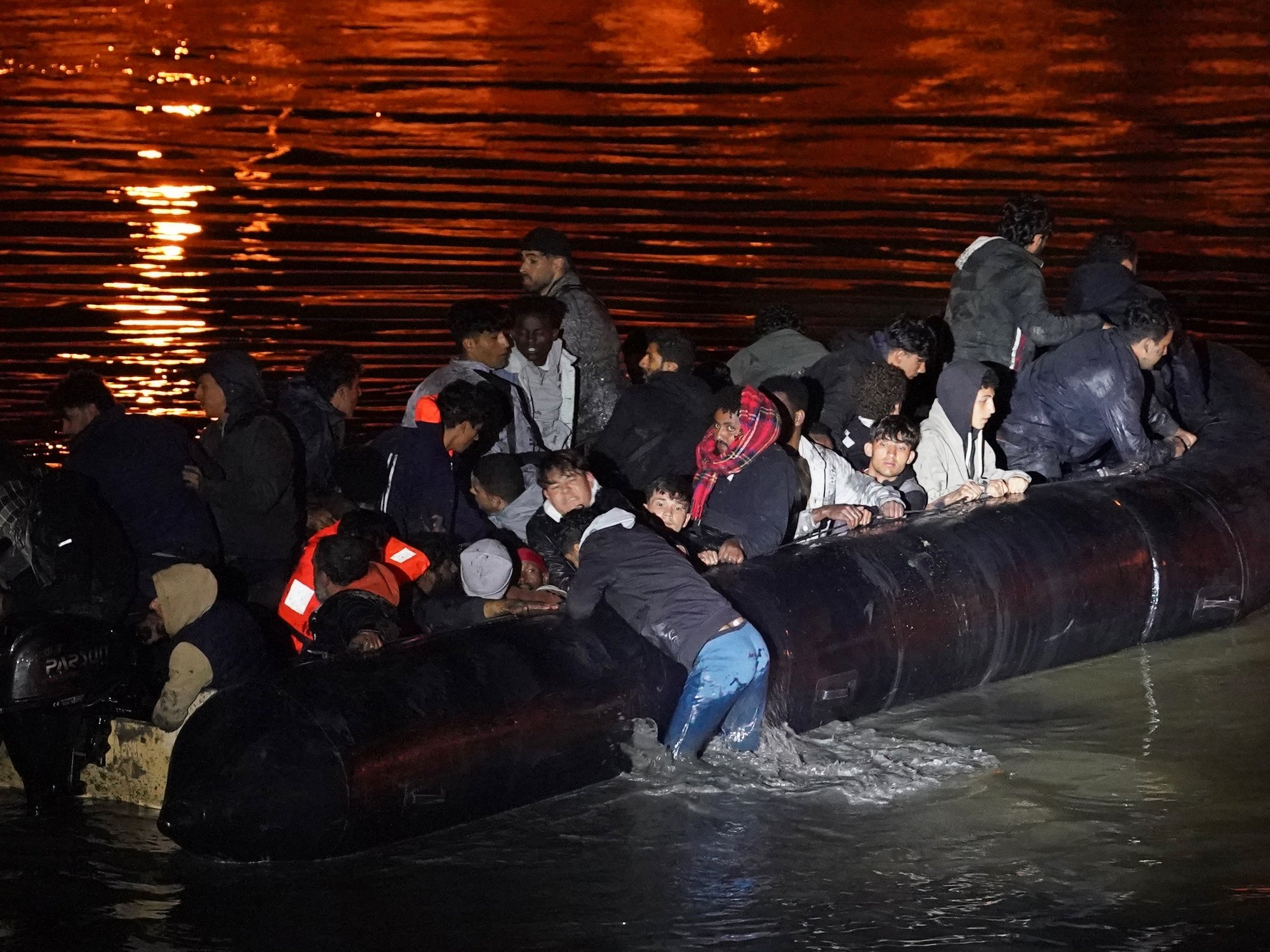 People thought to be migrants successfully launch a small boat from a riverbank in Gravelines, France