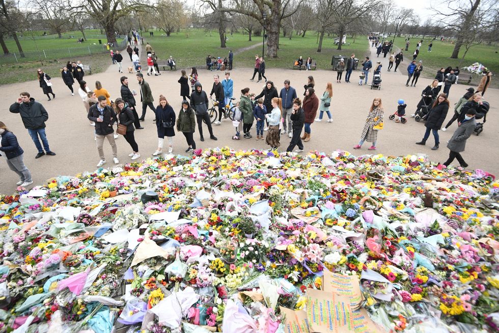 People viewing floral tributes left at the bandstand in Clapham Common, London, for Sarah Everard.