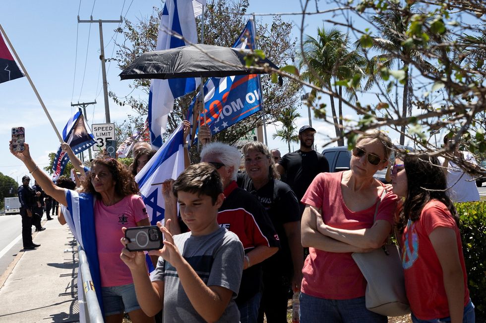 People wait for Israeli Prime Minister Benjamin Netanyahu\u2019s motorcade to drive past as he is expected to meet with Republican presidential candidate and former U.S. President Donald Trump at his Mar-a-Lago resort, in West Palm Beach