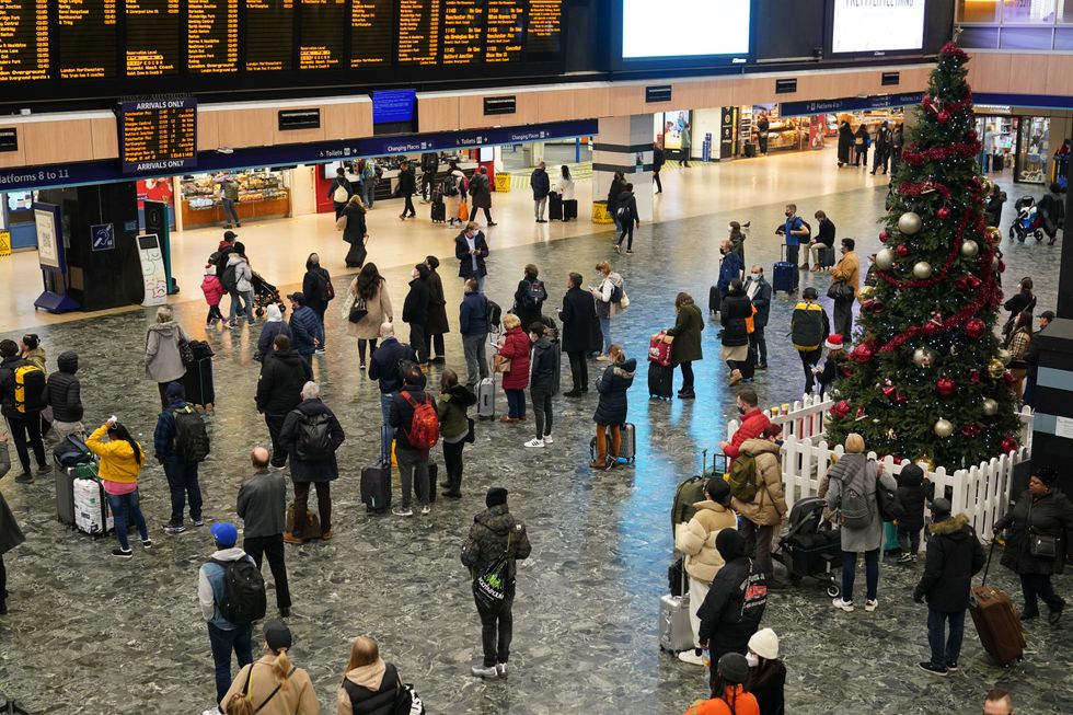 People wait for their trains on the concourse at Euston station in London.