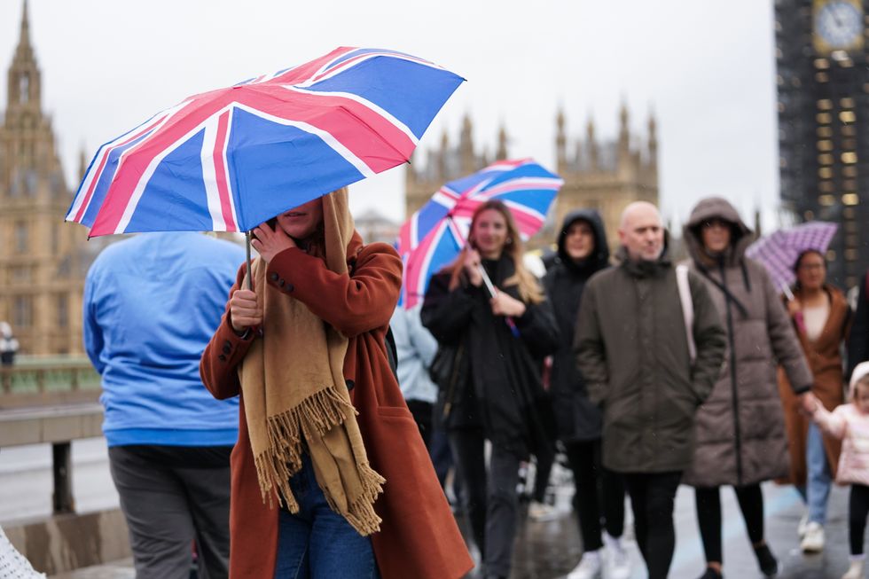 People walk across Westminster Bridge in the rain, in Westminster in London. Heavy rain and strong winds could bring flooding, travel disruption and power outages to parts of England and Scotland over the weekend. Picture date: Saturday October 2, 2021.