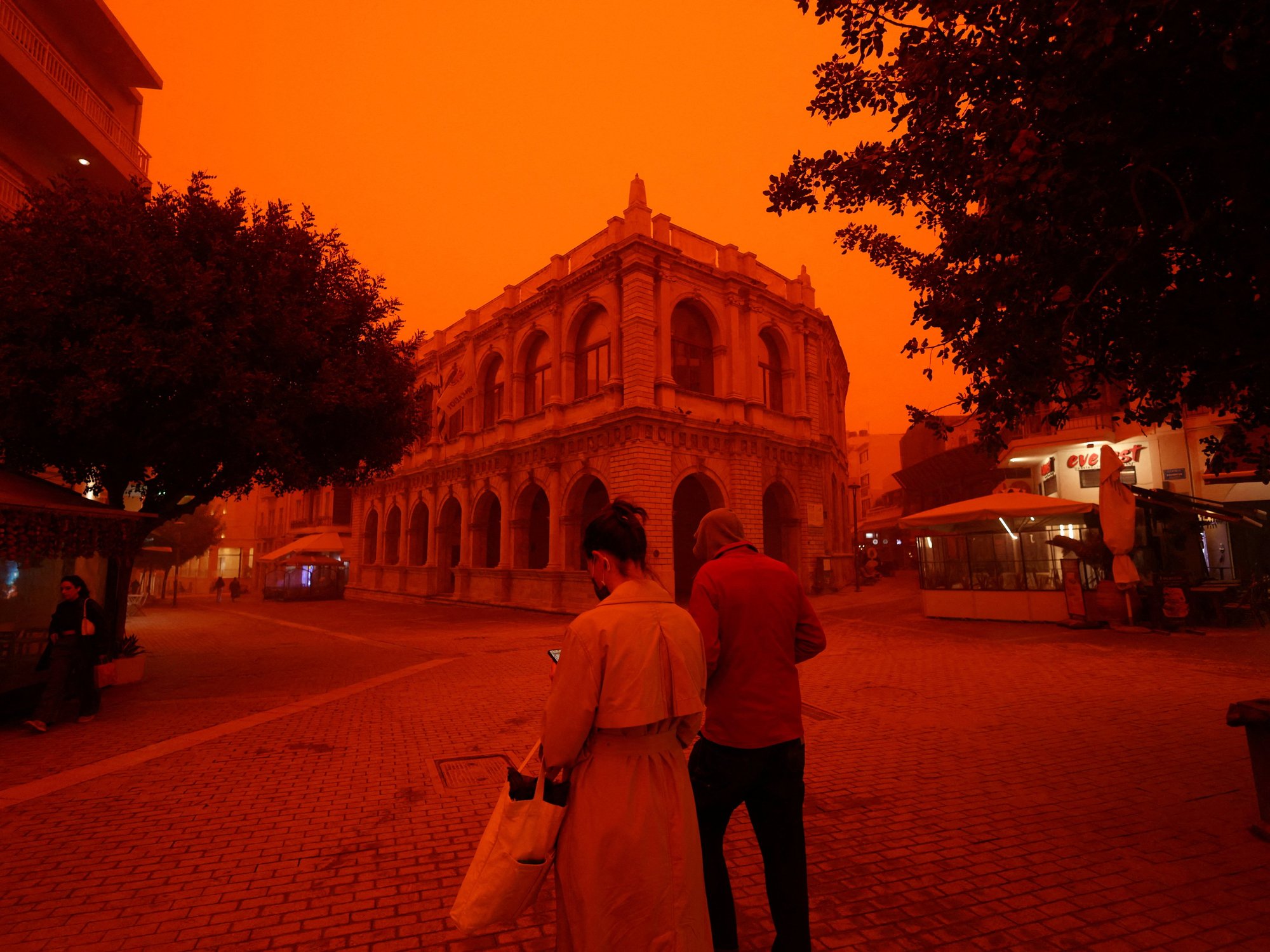 People walk amid a haze caused by sand dust from the Sahara, due to strong southern winds, in Heraklion