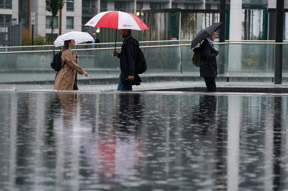 People walk by Centenary Square in Birmingham during a rainy morning