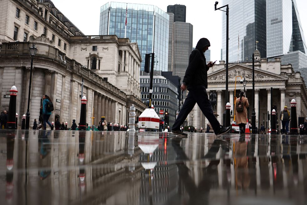 People walk by the Bank of England building (L) and Stock Exchange building (R), in the financial district, central London