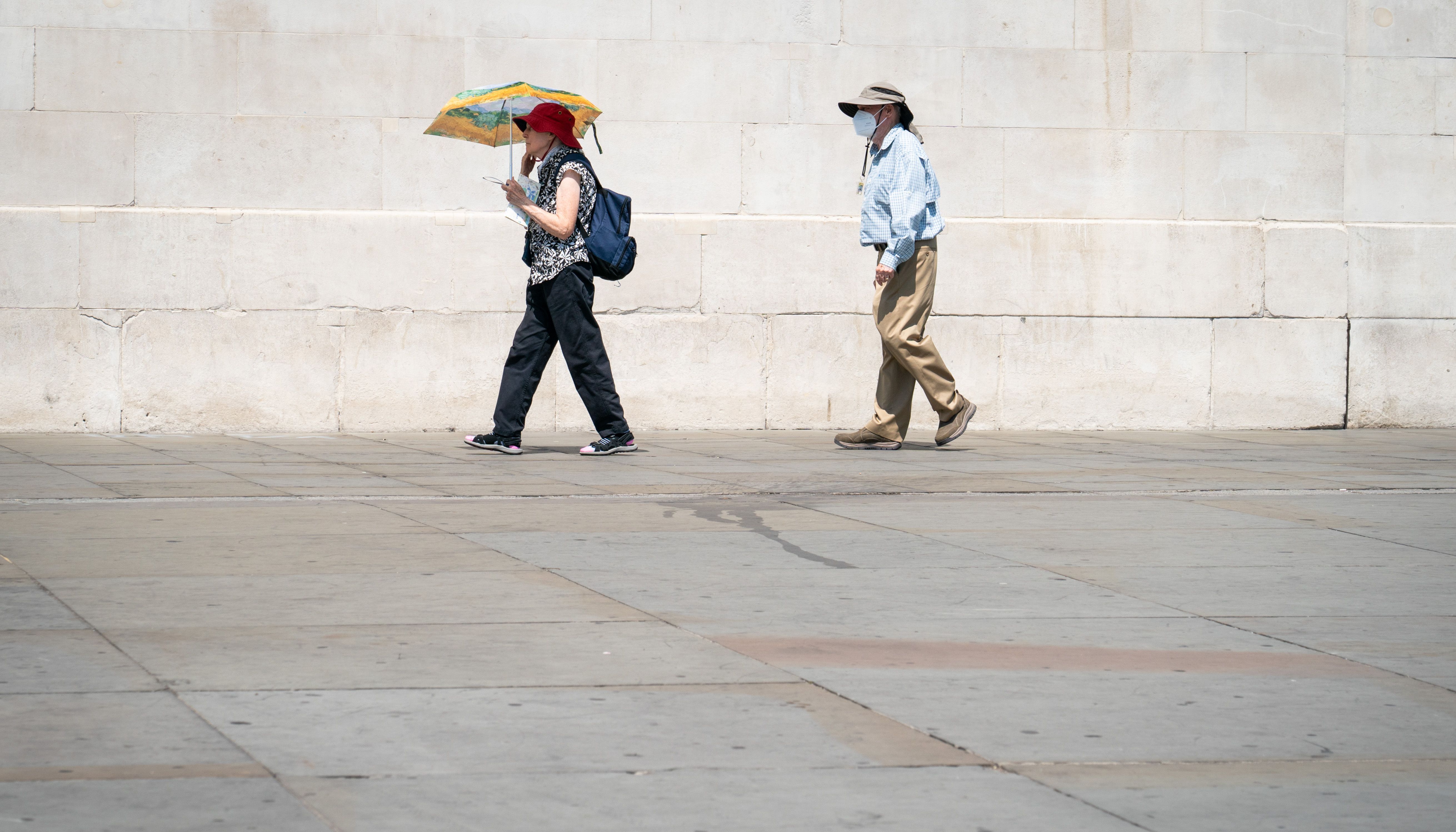 People walk in the sun in Trafalgar Square, central London
