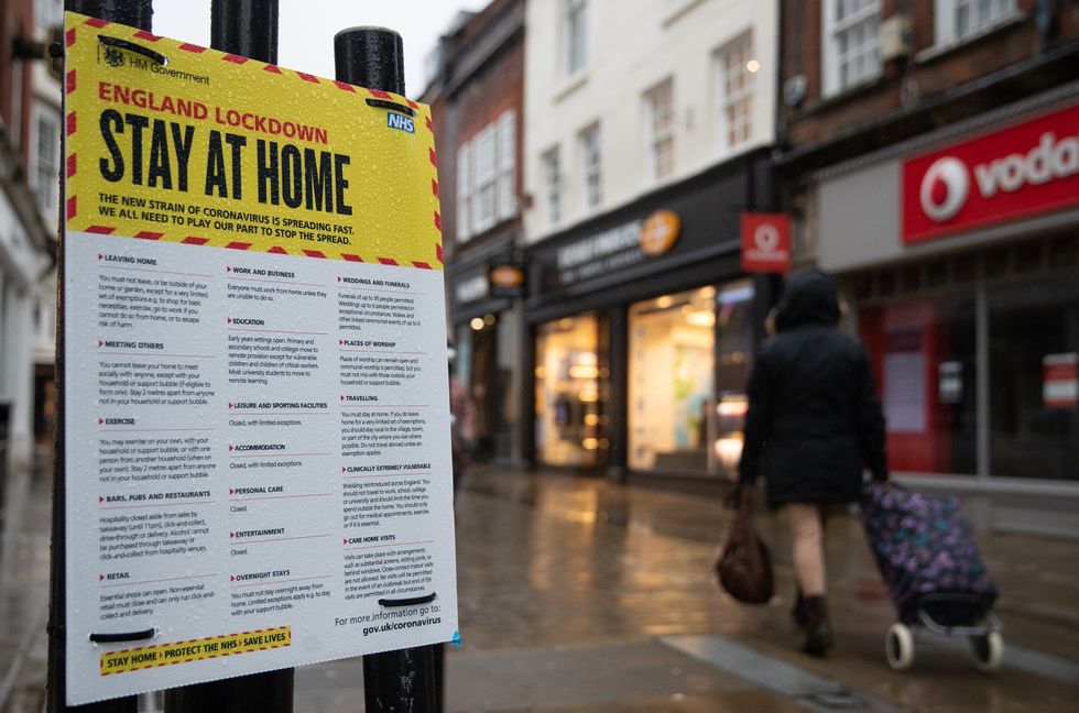 People walk past a Government sign warning people to stay at home on the High street in Winchester, Hampshire, during England's third national lockdown to curb the spread of coronavirus. Picture date: Wednesday January 20, 2021.