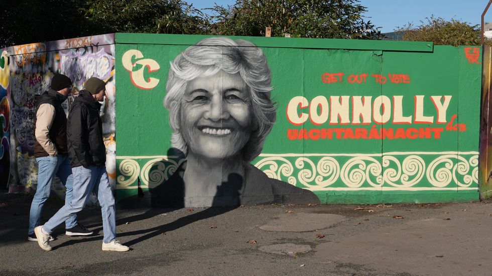People walk past a mural of Catherine Connolly by artist Emmalene Blake on South Dock Road in Dublin