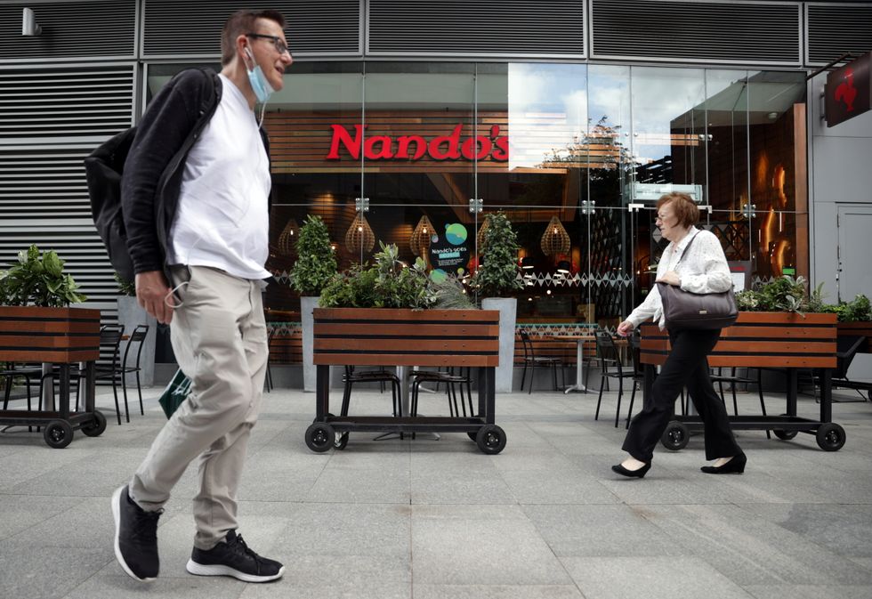 People walk past a Nando\u2019s restaurant in London.