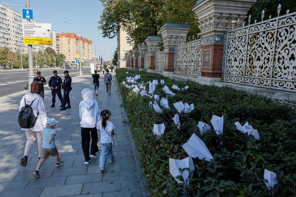 People walk past paper planes outside the French embassy in Moscow