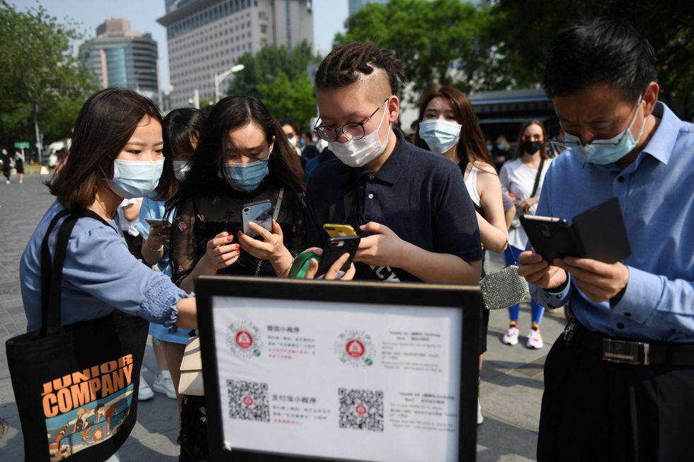 People wear face masks as a preventive measure against the coronavirus as they use a phone app to scan a code