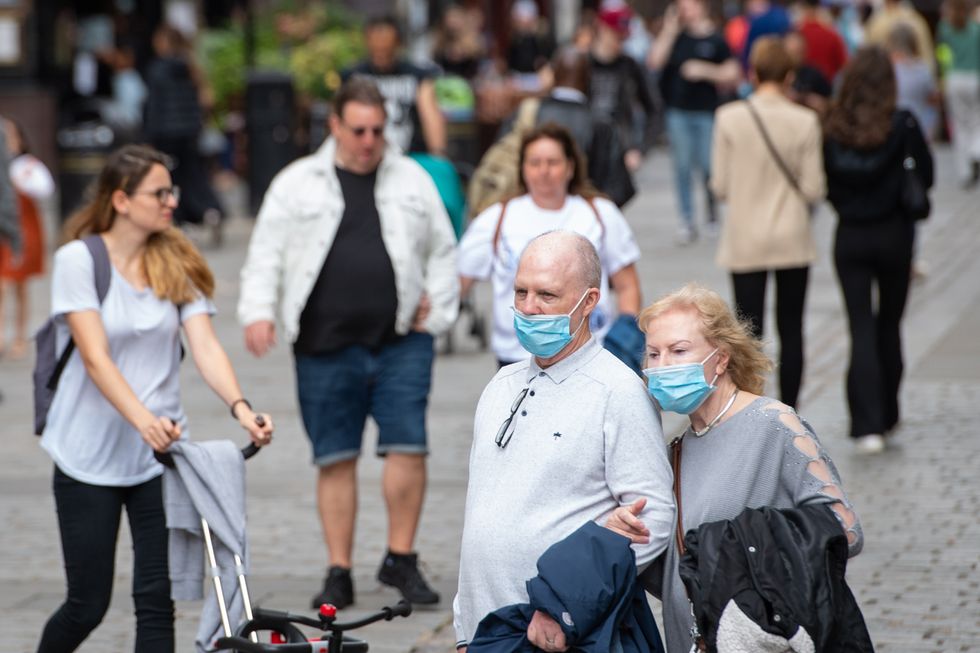 People wearing face masks watch a street entertainer in Covent Garden