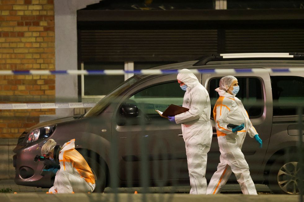 People work at a shooting scene as Belgian police secure the area, in Brussels