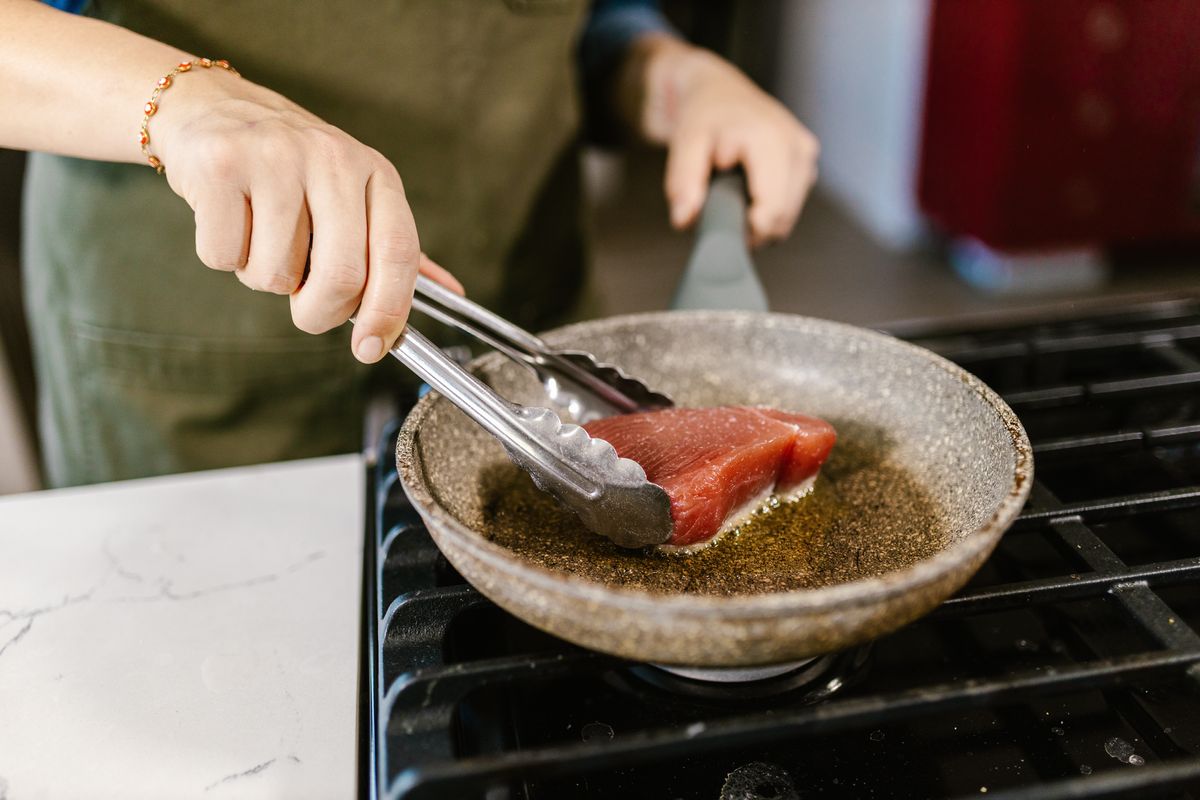 Person cooking a piece of steak