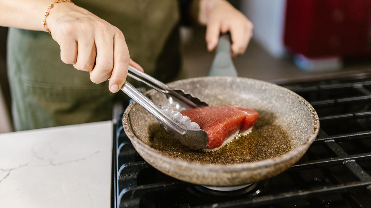 Person cooking a piece of steak