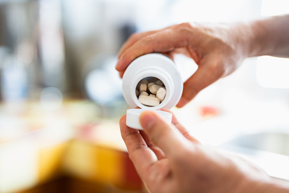 Person emptying supplements bottle