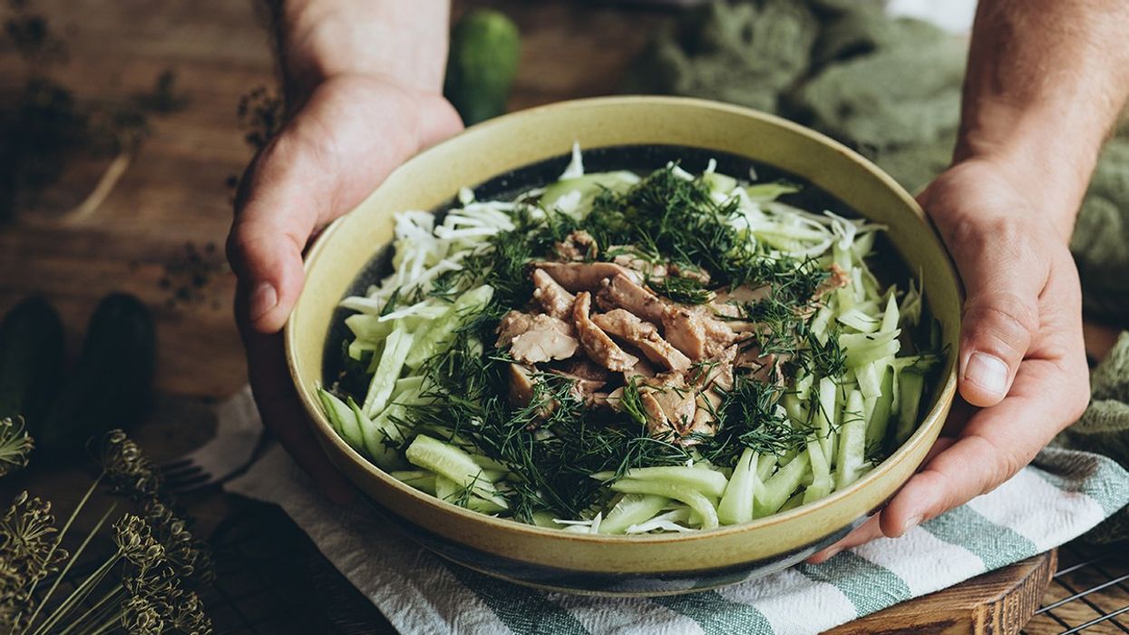 Person holding bowl of leafy greens and cod liver