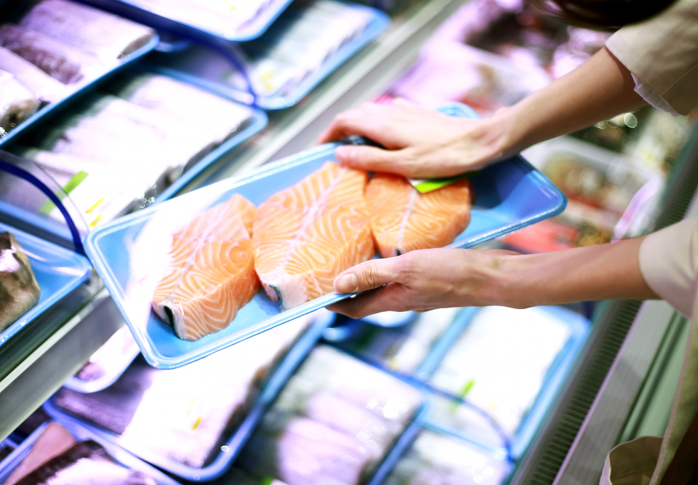 Person holding packaged salmon in a shop