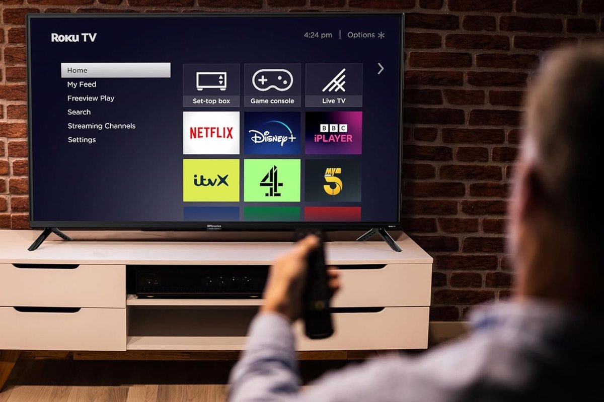 Person holding remote in front of Roku TV