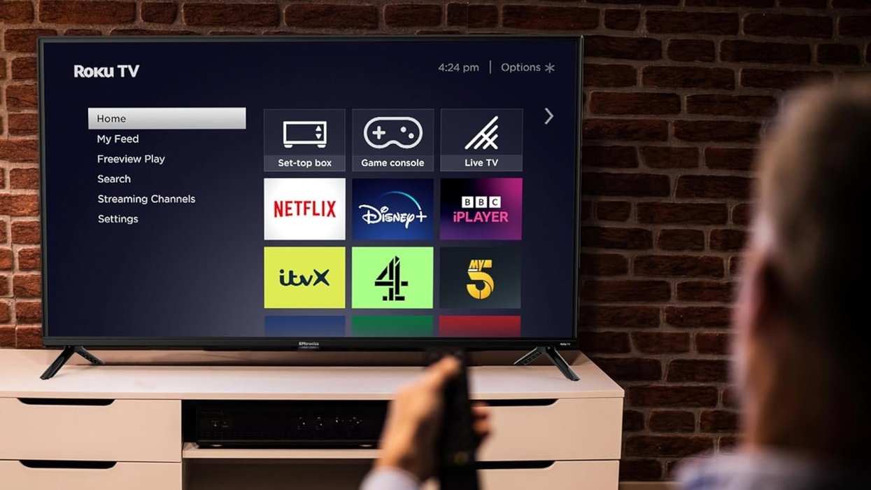 Person holding remote in front of Roku TV