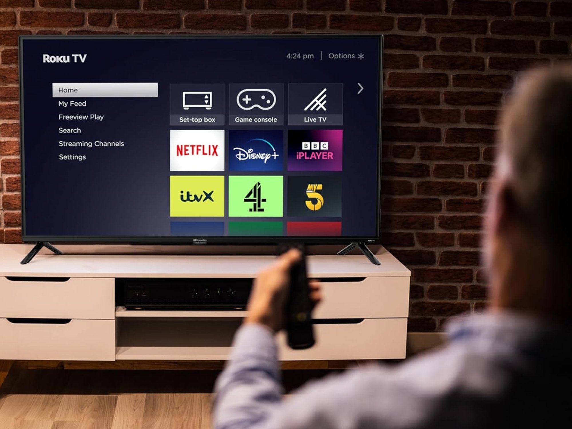 Person holding remote in front of Roku TV