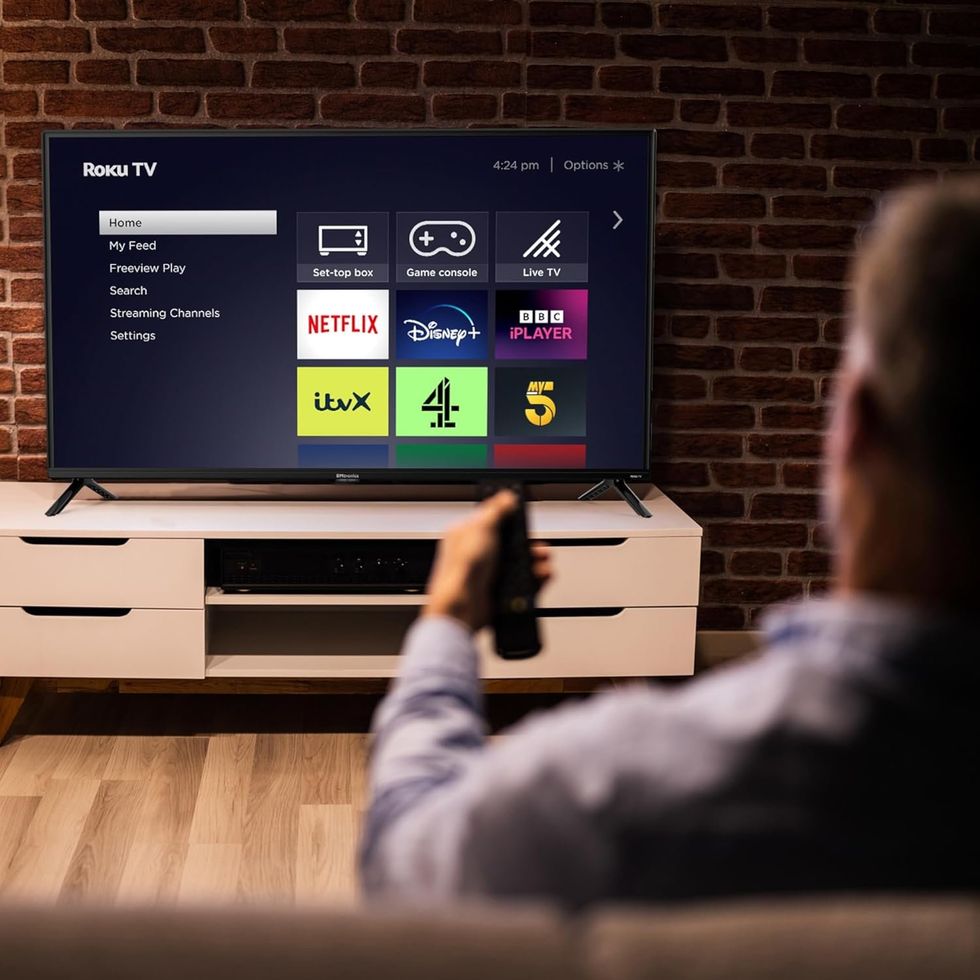 Person holding remote in front of Roku TV