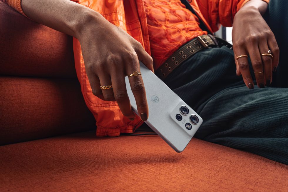 person holding the motorola moto g75 in grey on sofa