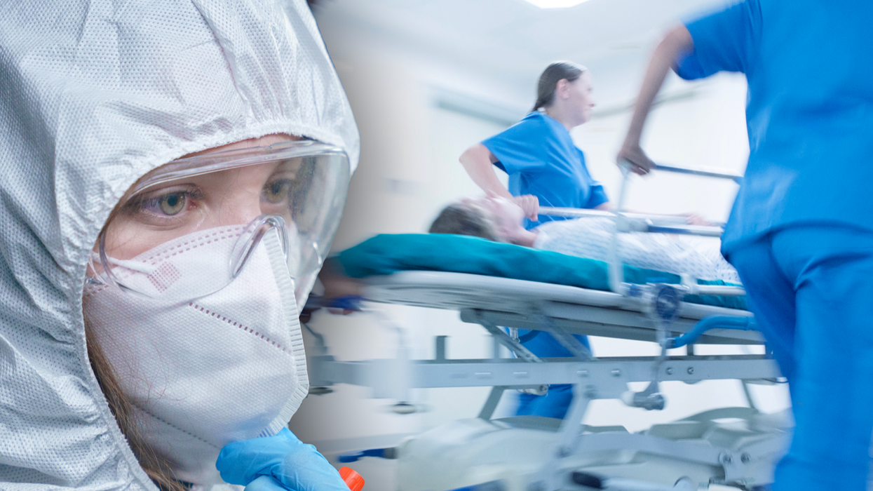 Person in a hazmat suit in a busy hospital corridor