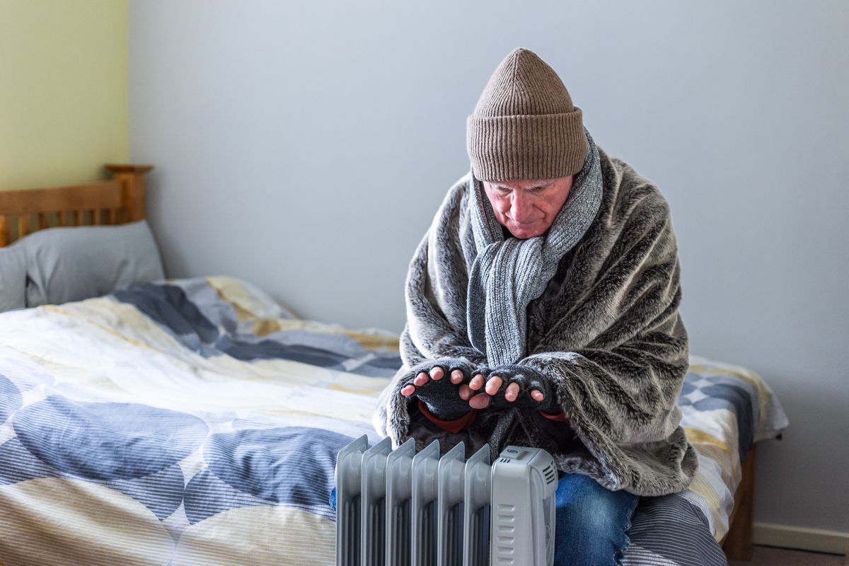 Person in blanket looks very cold by heater