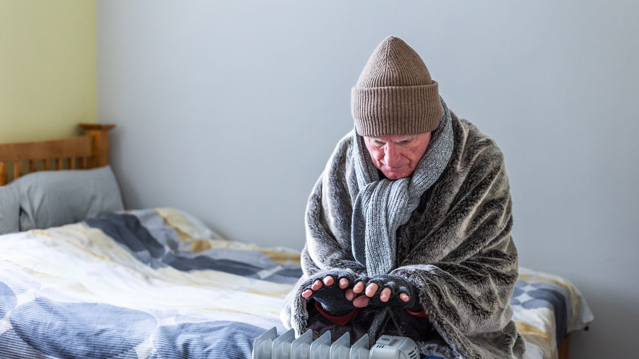 Person in blanket looks very cold by heater