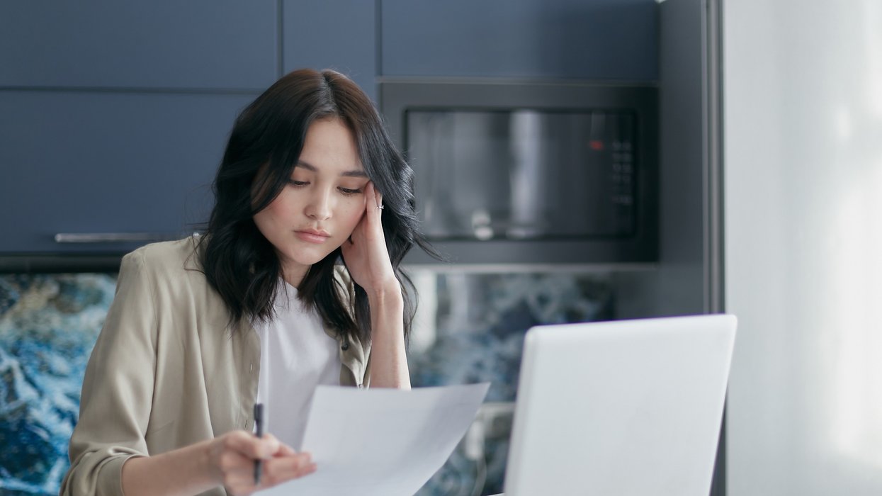 Person looking at document beside laptop