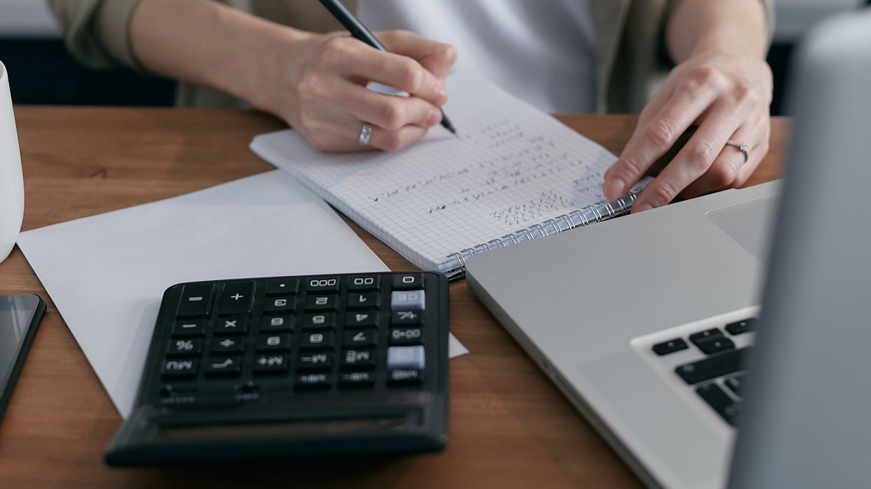 Person looking at finances on notepad and laptop