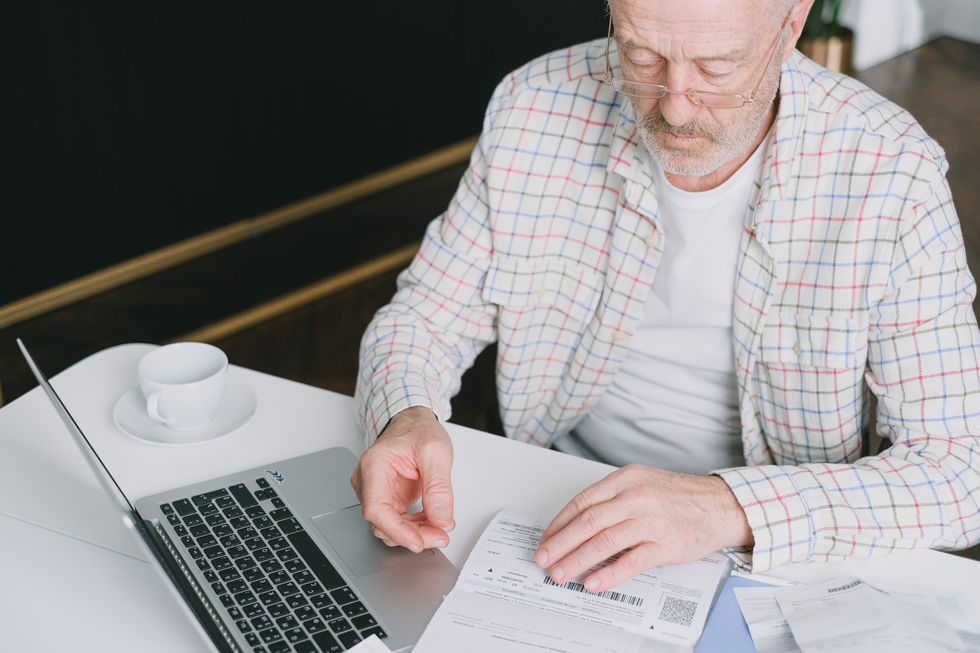Person looking at financial statement beside laptop