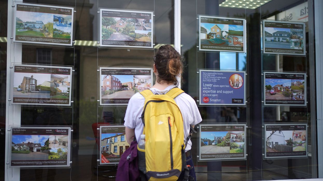 Person looking at houses for sale in estate agent window