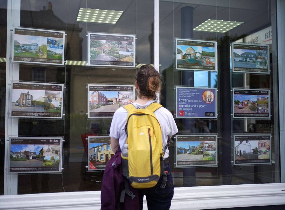 Person looking at properties for sale in window of estate agents