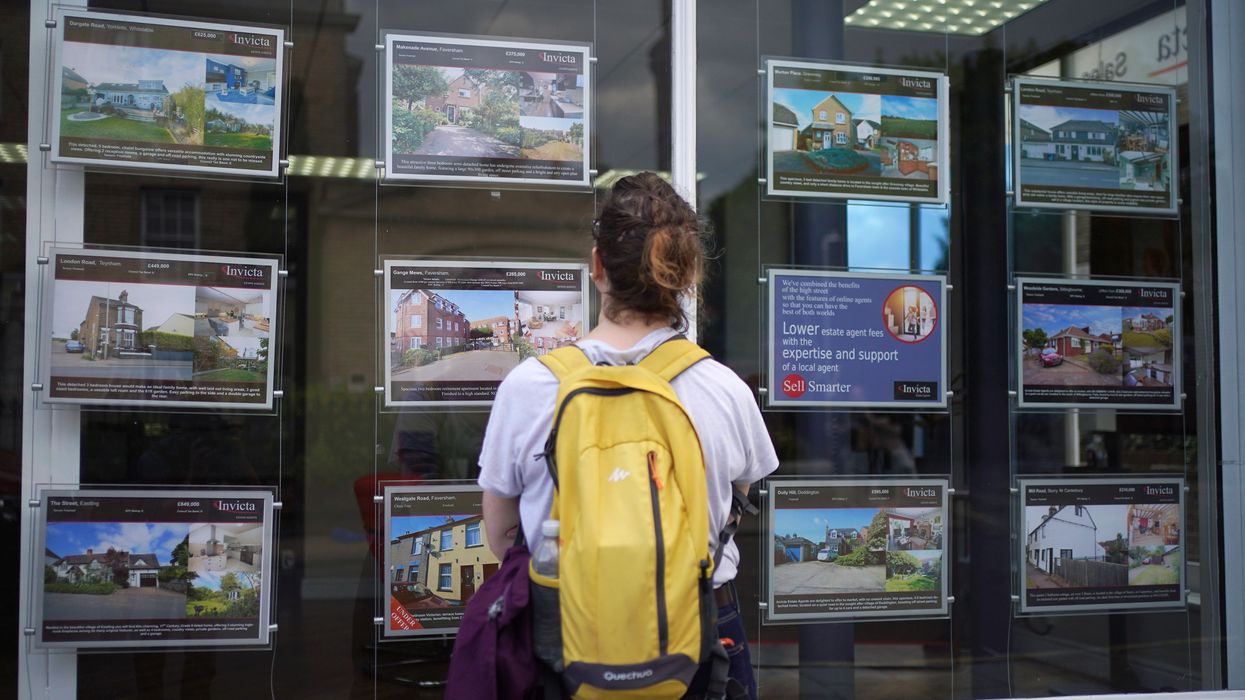 Person looking at property for sale in estate agent window