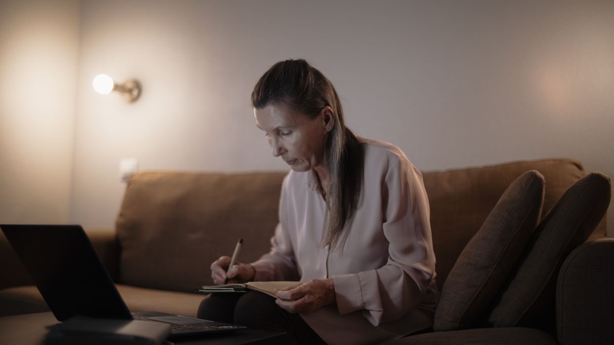 Person looks at finances on sofa with laptop in front of her