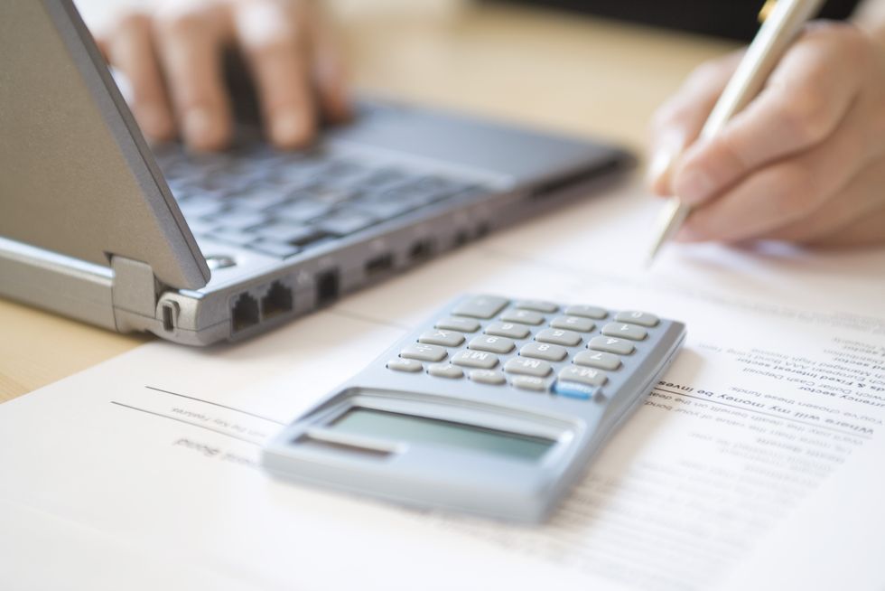 Person looks at laptop and calculator