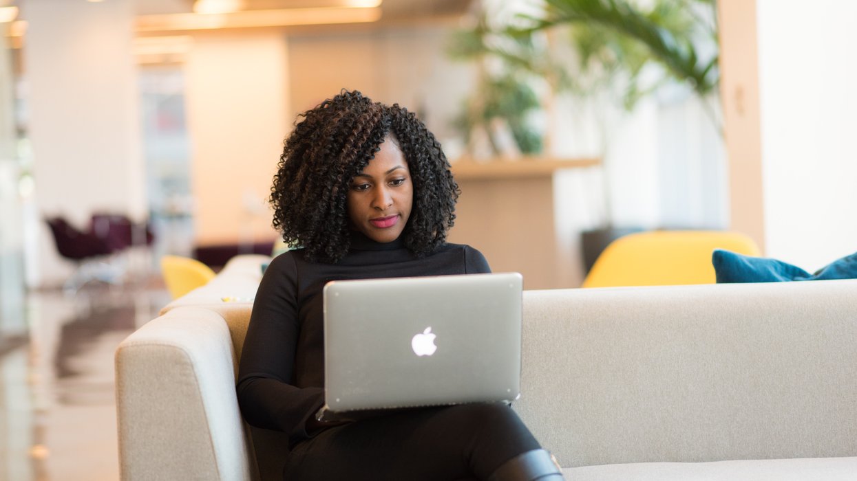 Person looks at laptop on sofa