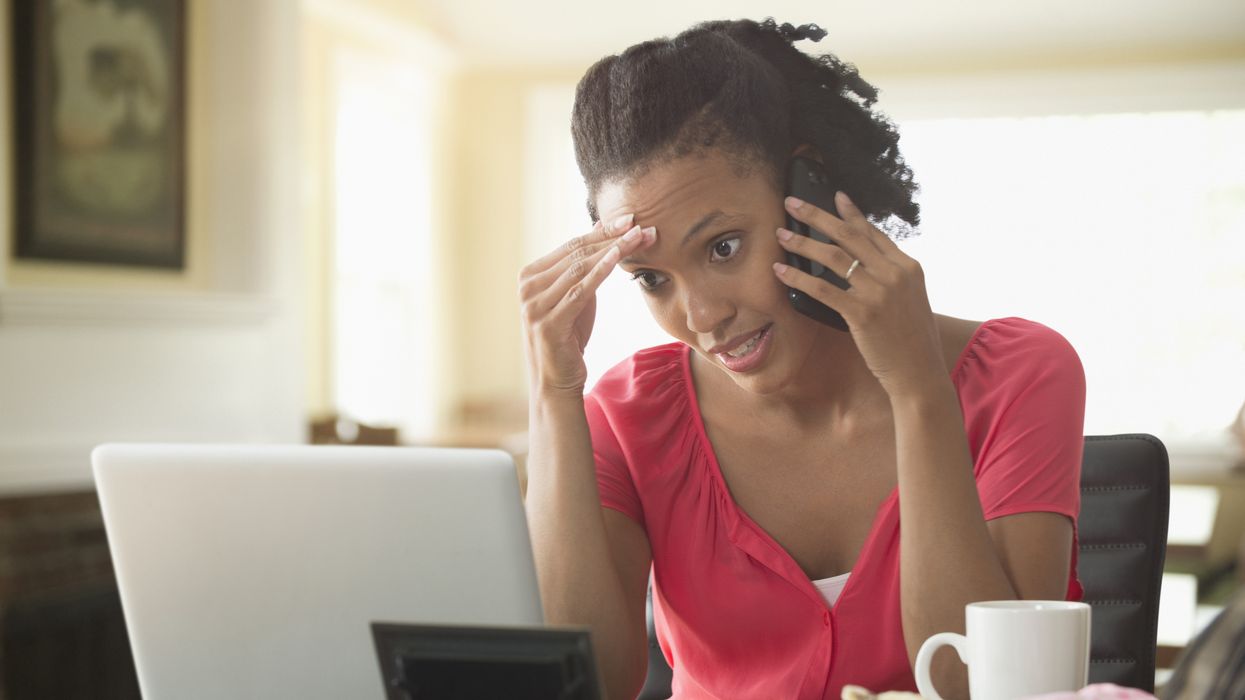Person looks at laptop while on phone