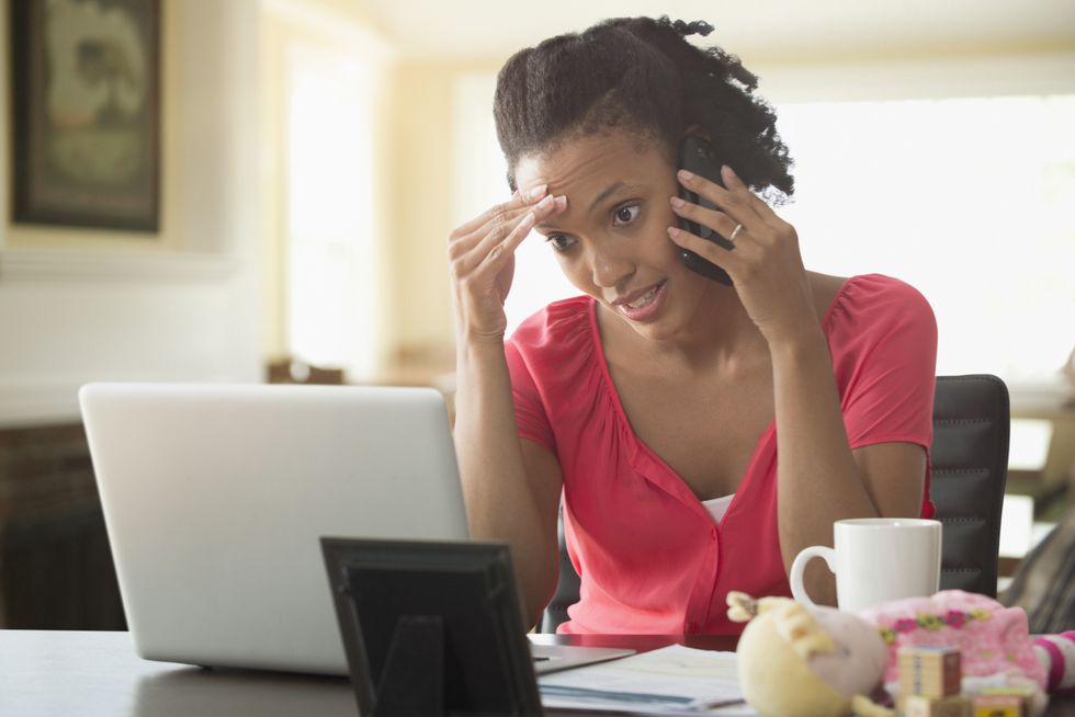 Person looks at laptop while on phone